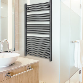 Tall matt black heated towel rail radiator in a bathroom.