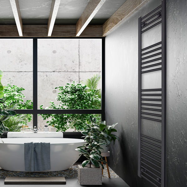 Tall black heated towel rail radiator in a bathroom with a freestanding bath