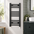 Black towel radiator with standard heating element fitted at the bottom in a bathroom setting