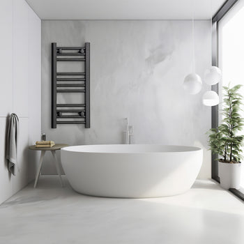 Black heated towel rail radiator mounted beside a freestanding bath