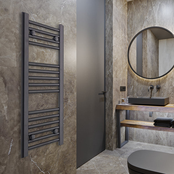 Black heated towel rail radiator mounted on a grey bathroom wall